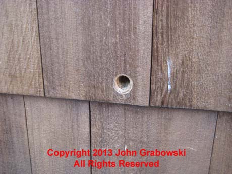 The hole in the wood siding was made using two spade drill bits