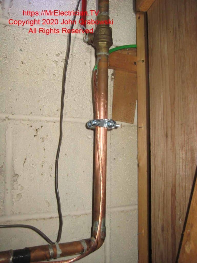 A clean copper pipe after the water meter with a new grounding clamp and a new grounding electrode conductor attached. From here, the grounding conductor goes to the main electrical panel or a disconnect switch. CLICK HERE to see Water Pipe Ground Clamps at Amazon