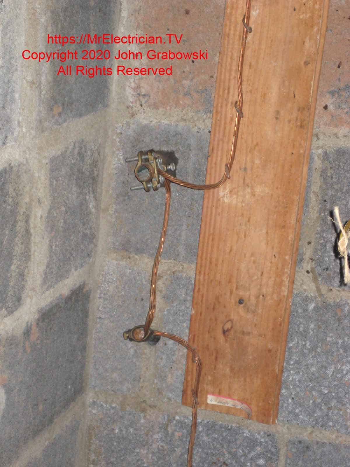 Installation of a ground rod through a basement wall with the grounding electrode conductor also connected to the nearby old water service pipe