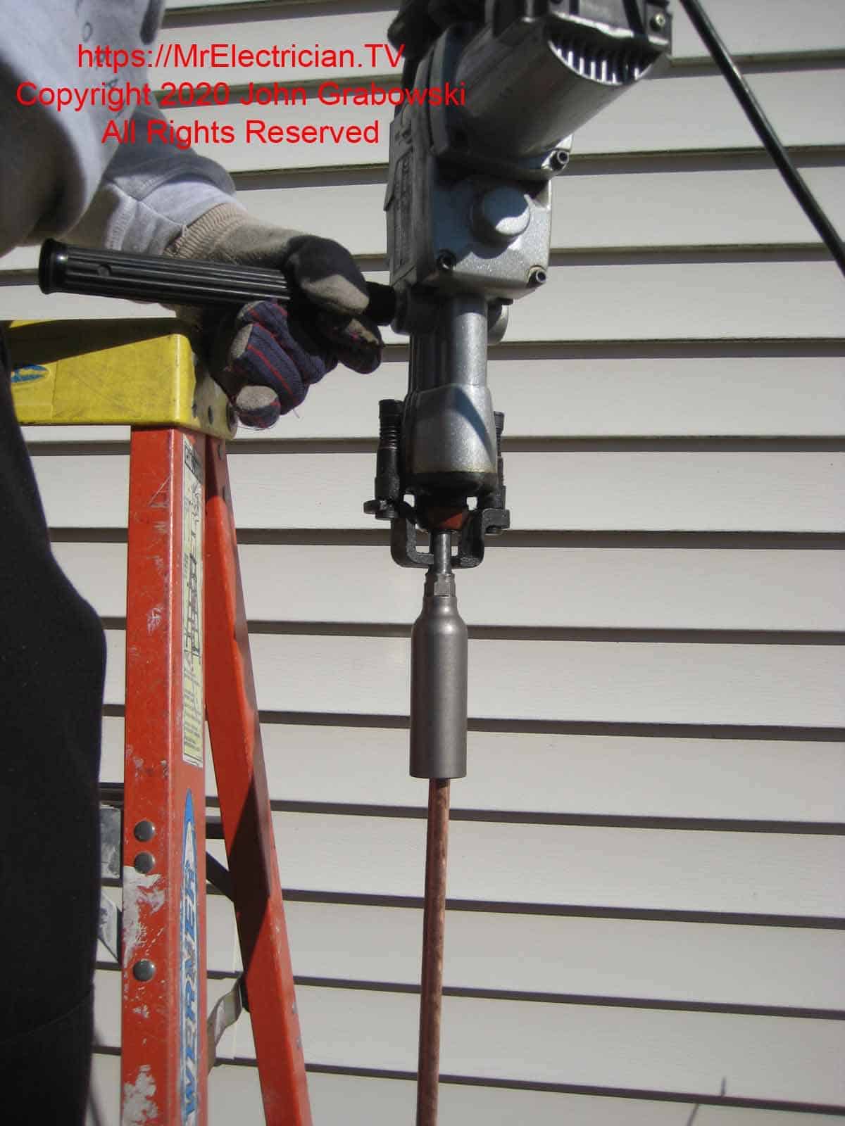 Close shot of rotary hammer driving ground rod into the ground
