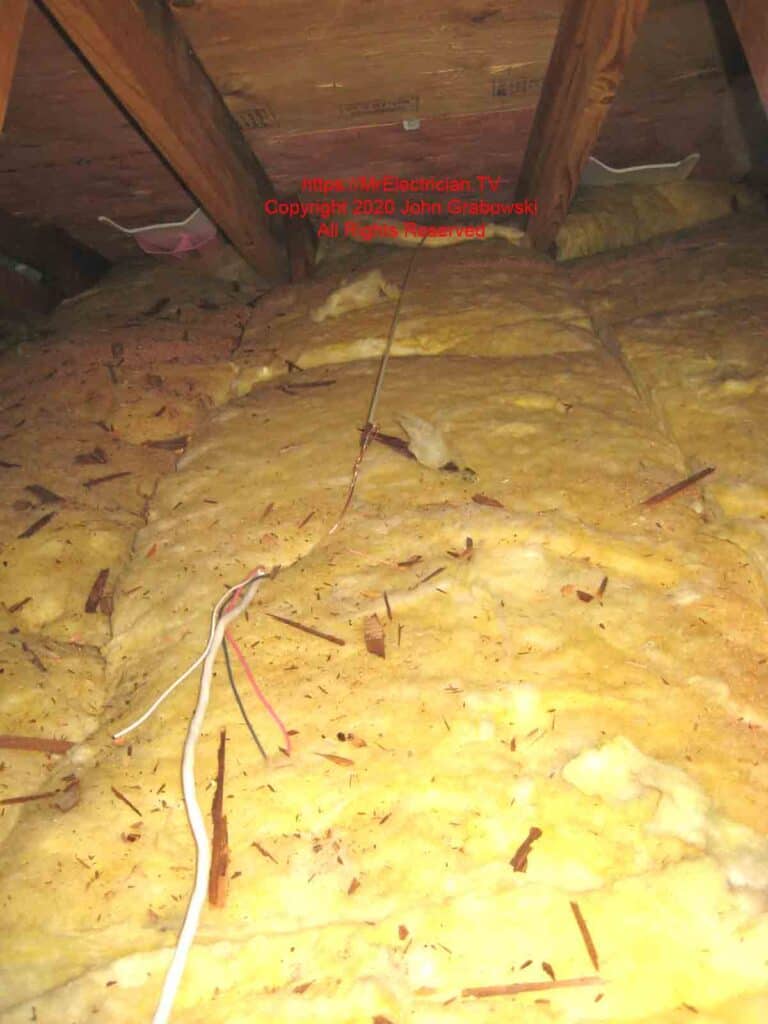 Fiberglass rod pulling a 14/3 Romex cable across attic insulation