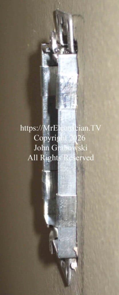 A metal electrical outlet box has its ears reversed and is mounted to the wall with Madison Bars. When ceramic tile is added to the wall the box will be flush with the finished surface.