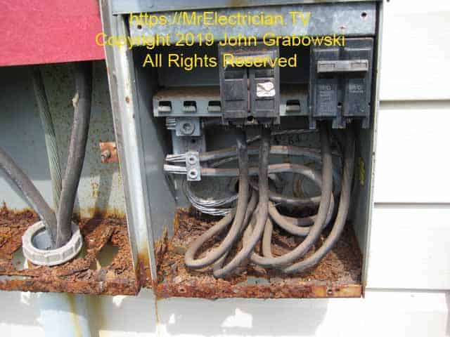 View of the inside of the circuit breaker enclosure on a rusty 4 gang electric meter base