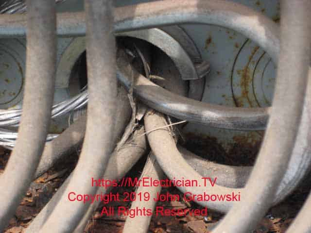Tenant load wires entering the rear of the rusty four gang meter base