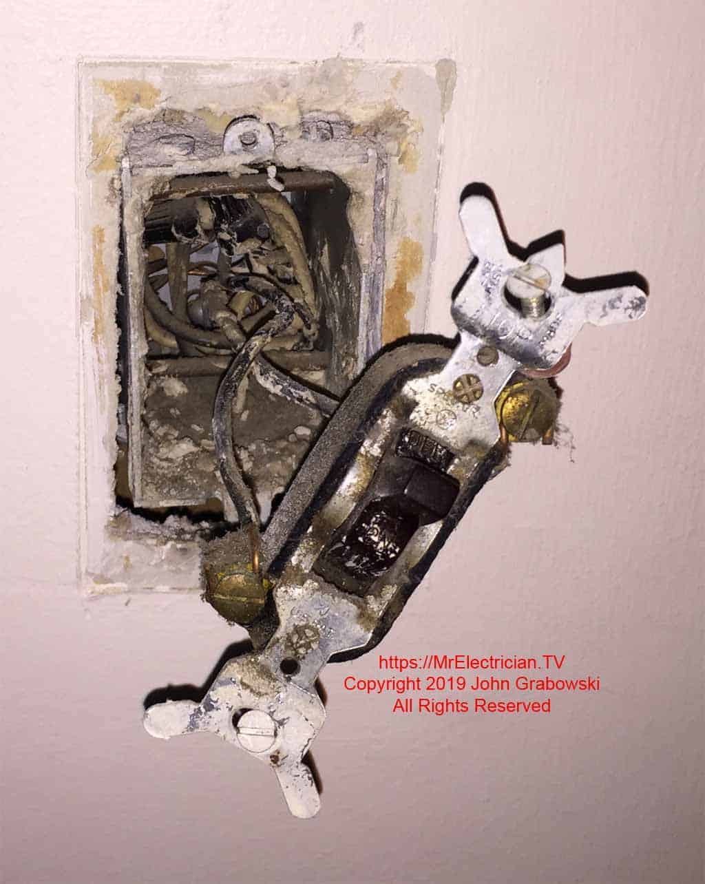 An old electric wall switch removed from the electrical box, but still connected