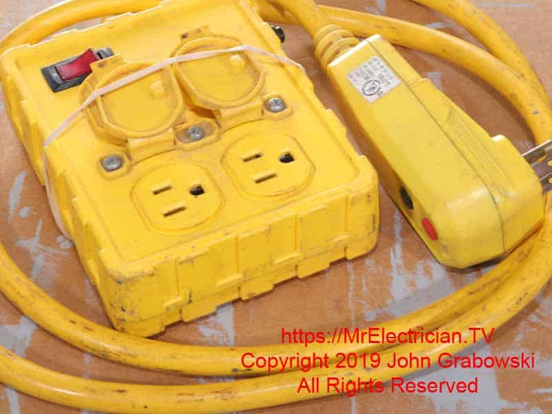 A GFCI protected yellow 4-way portable electrical box on a short cord