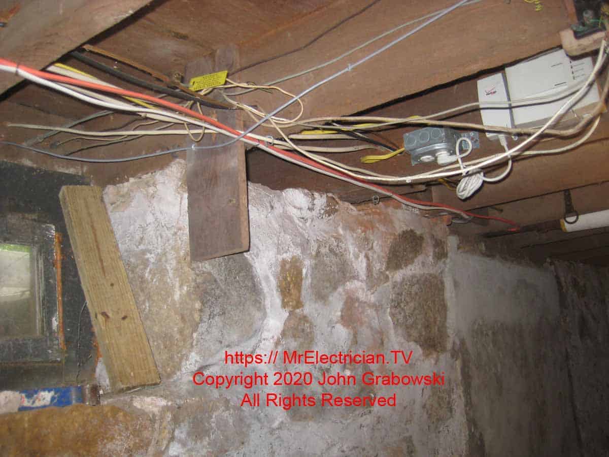 Solid rock basement foundation with some wires attached to the overhead joists