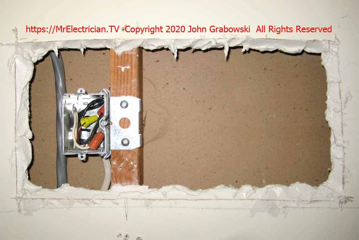 Adjustable box in the hole in the wall. The edges of the hole are buttered in Joint Compound for patching the hole