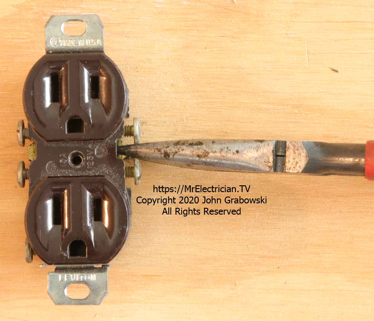 A duplex electrical receptacle having its side tab broken off by needle nose pliers