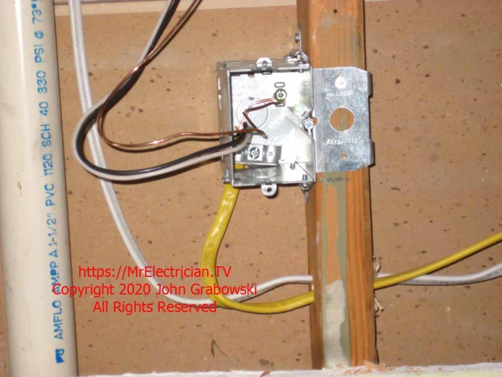 Close shot of a metal adjustable outlet box, mounted on a wood wall stud, with 12/2 Romex type NM-B electrical wiring entering from the bottom