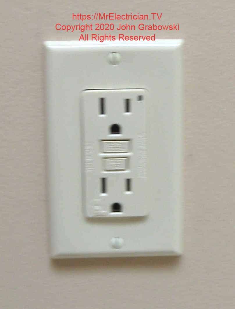 Finished almond colored GFCI electrical outlet installed in a wall