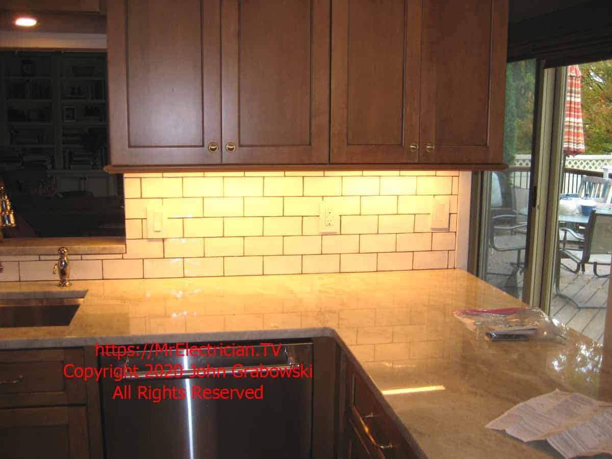 The finished kitchen cabinets with, counter top, backsplash, undercabinet lighting and electrical outlets ready to use