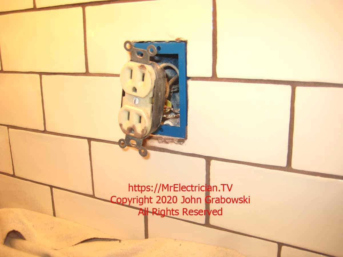 Old kitchen backsplash electrical receptacle in the new ceramic tile backsplash with a one-gang, 1/2", blue ReceptXtender receptacle box extender