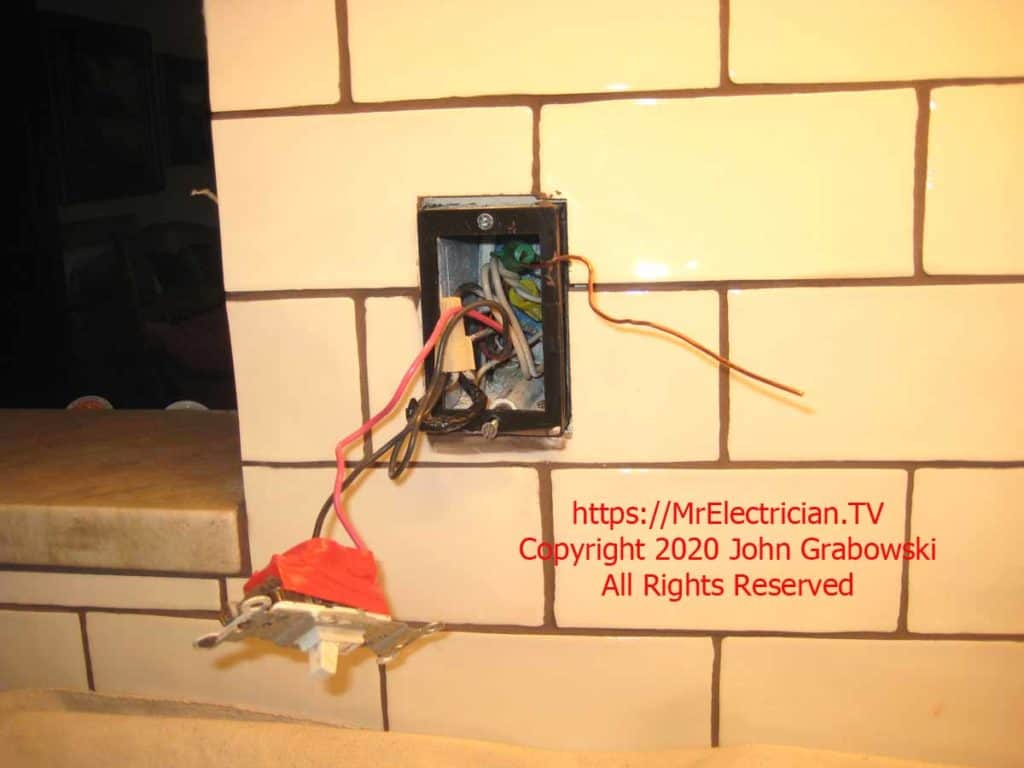 An old wall switch hanging from the switch box with a black, 3/4" ReceptXtender receptacle box extender attached