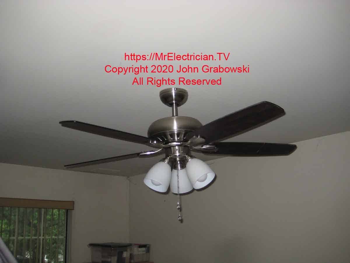 Ceiling fan with an attached light kit hanging from a ceiling