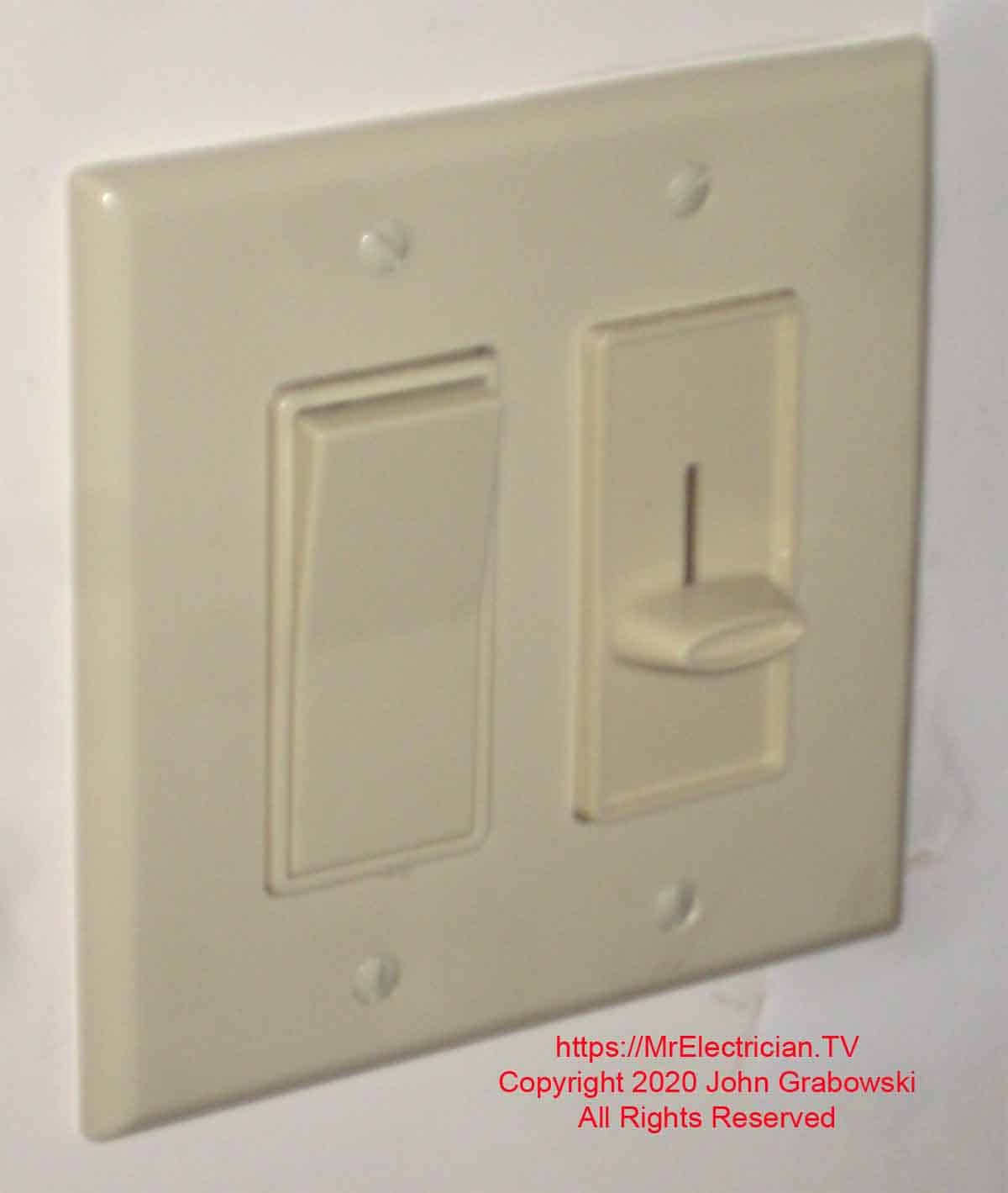 The finished wall switch and dimmer in a two gang switch box.
