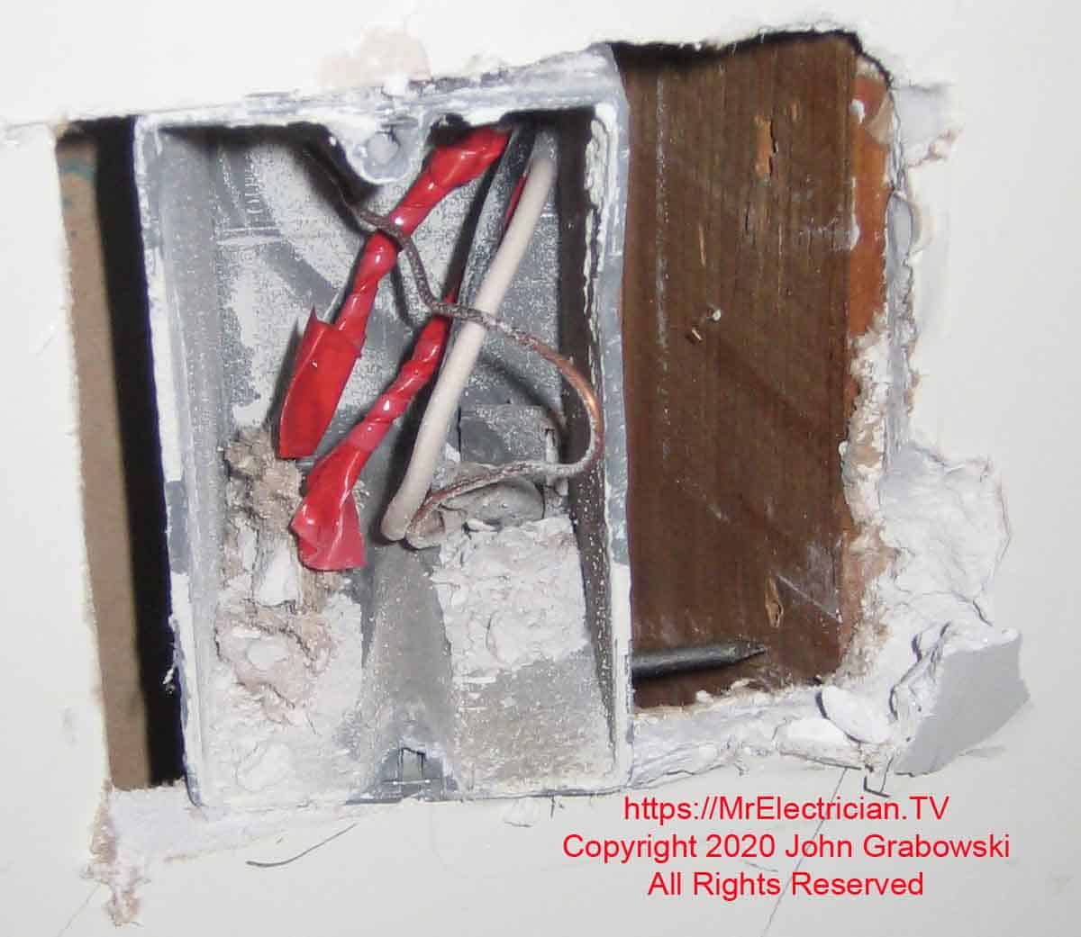 A one-gang plastic switch box separated from the wall stud.