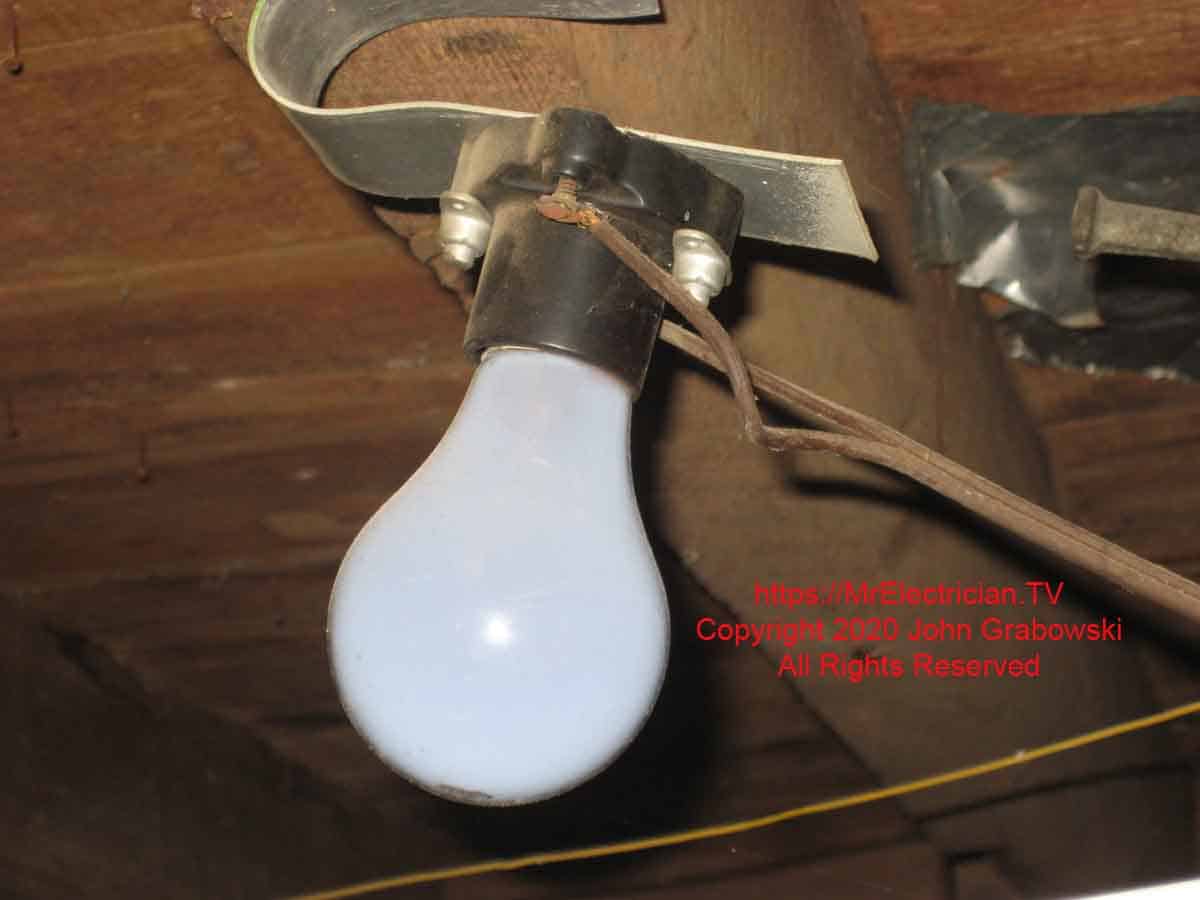 A light bulb socket with exposed electrical terminals and unsafe wiring.