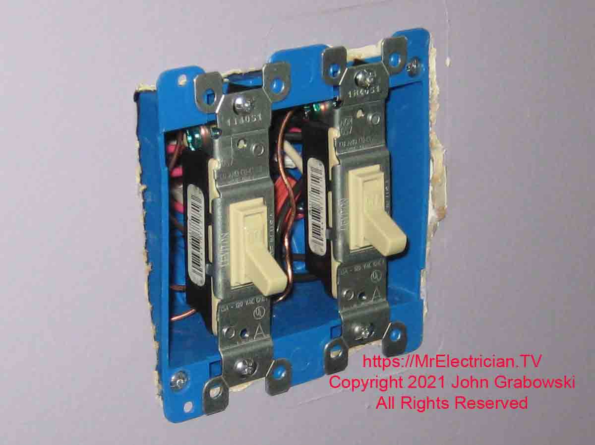 Two switches mounted to the two gang switch box without a finish wall plate