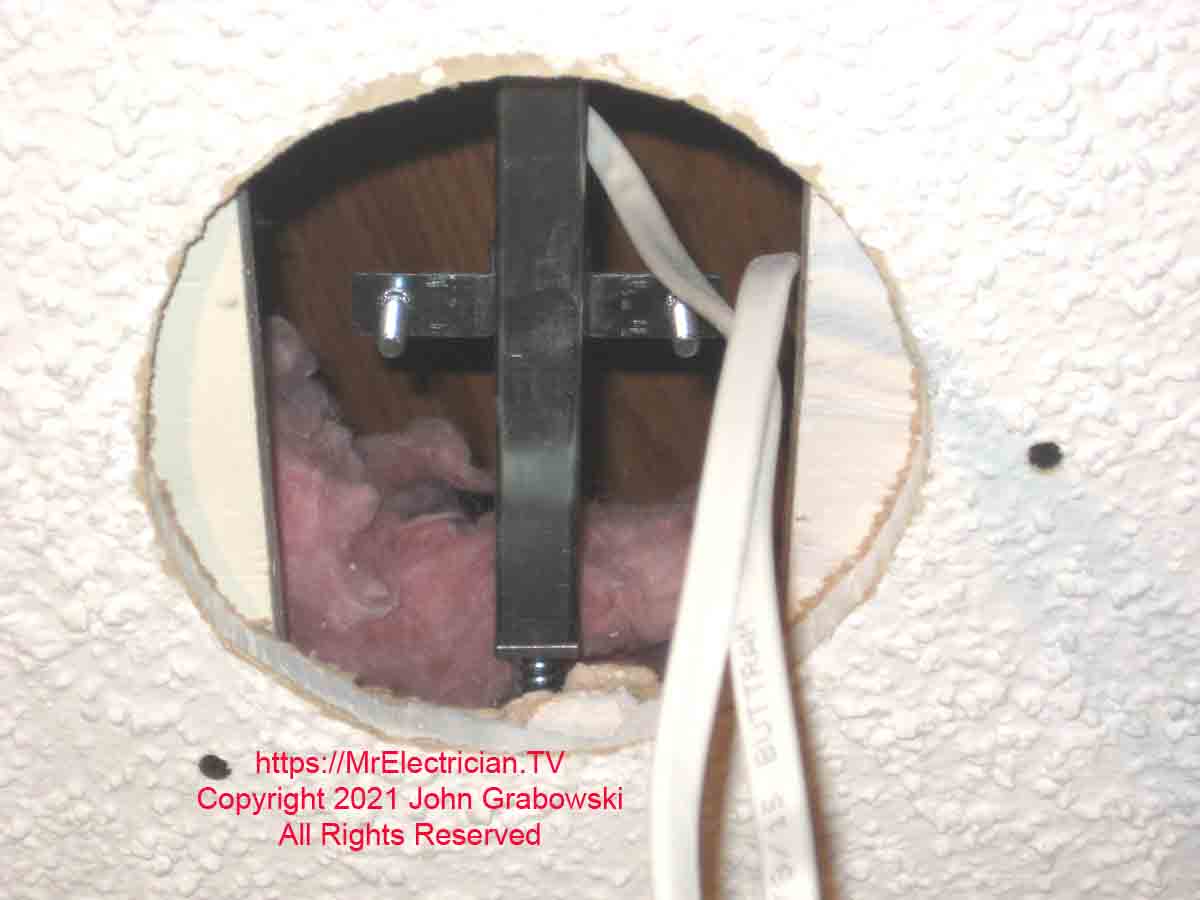 A ceiling fan brace installed inside of a hole that was once occupied by a recessed light