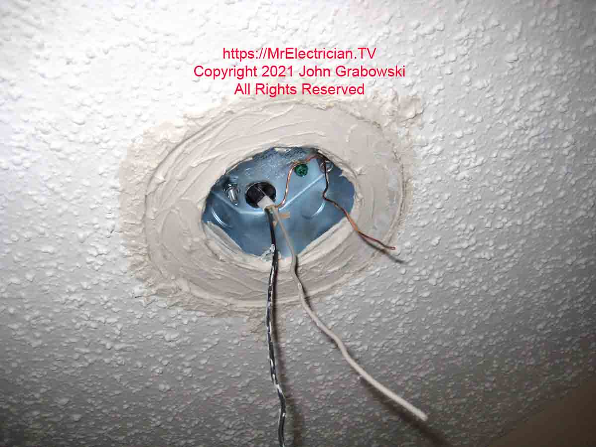 A patched ceiling hole formerly occupied by a recessed light, now with a ceiling fan box