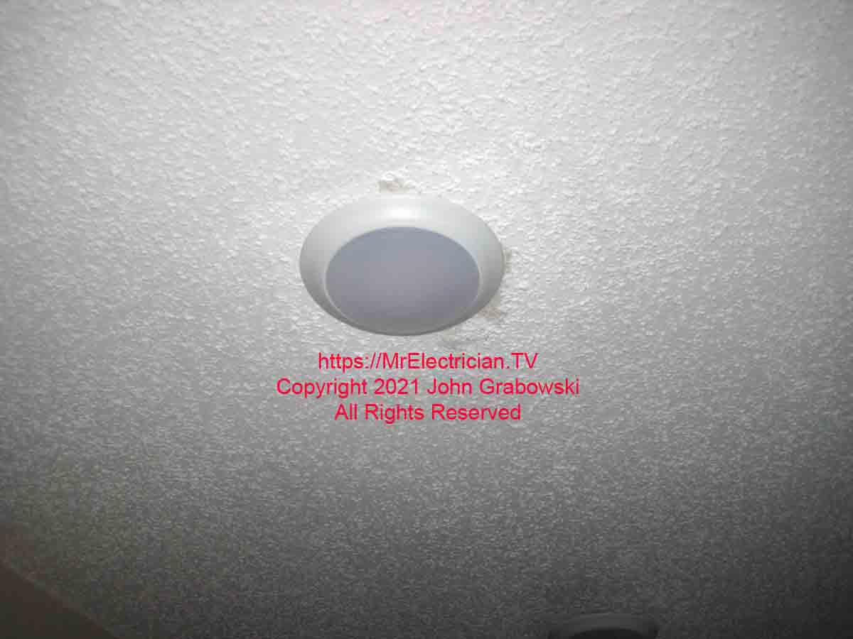 A single LED disk light mounted on the textured ceiling
