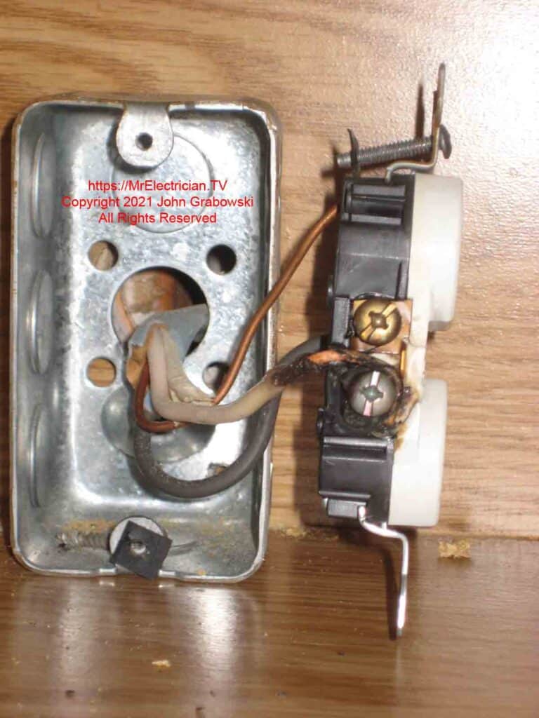 A burned wire terminal and wire insulation on an electrical outlet that had been arcing for some time due to a loose connection