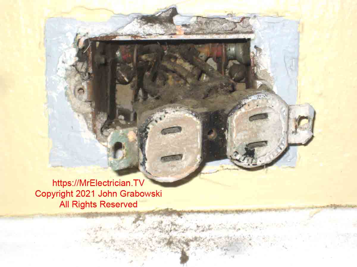 An old two-prong ungrounded electrical outlet ready for replacement with a three-prong outlet