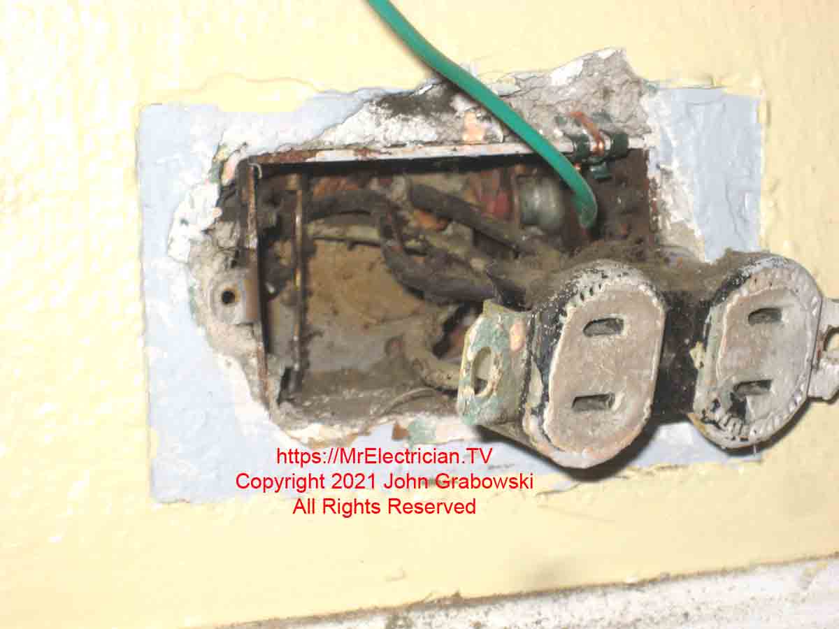 A two-prong ungrounded electrical outlet with a grounding pigtail wire attached to the metal box using a grounding clip. This is one method of how to ground a three-prong outlet