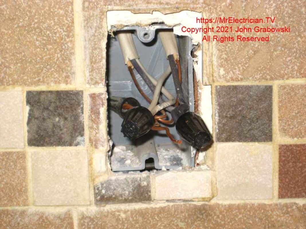 An outlet box in the wall with a broken screw hole