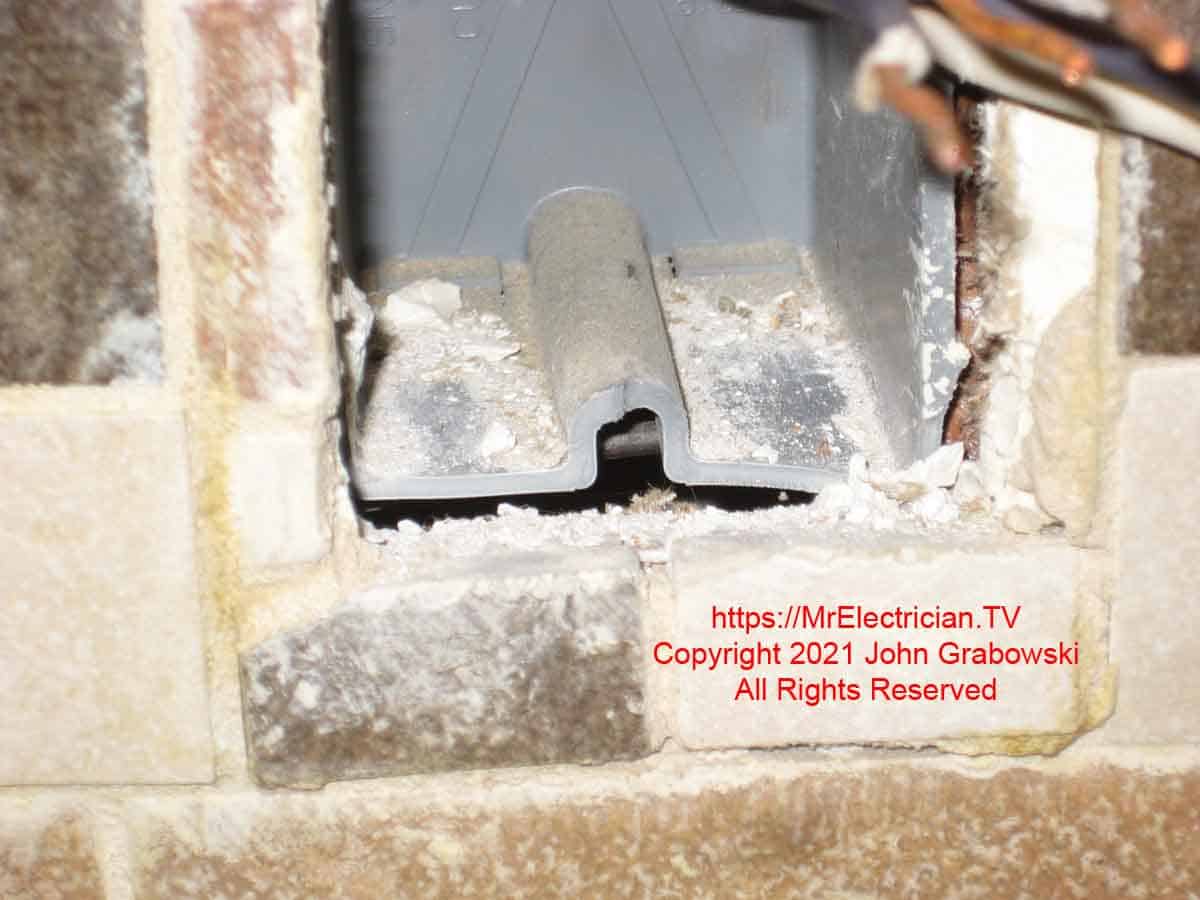 Close shot of a broken outlet box screw hole on a plastic outlet box mounted in a kitchen backsplash wall