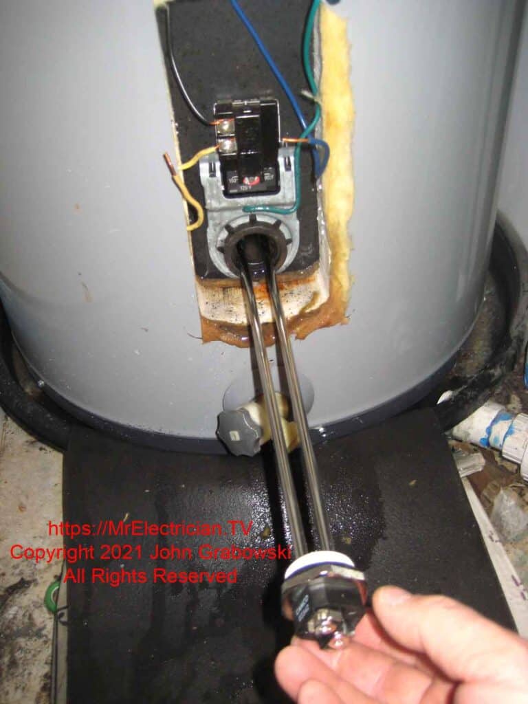 A new electric water heater heating element is being installed into the water heater tank
