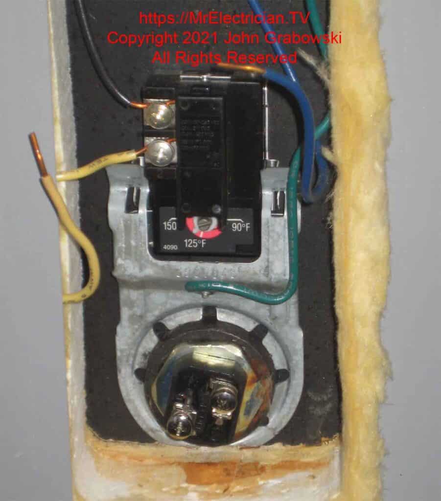 The lower thermostat and heating element on an electric water heater tank. The wires for the heating element are disconnected for testing the element.