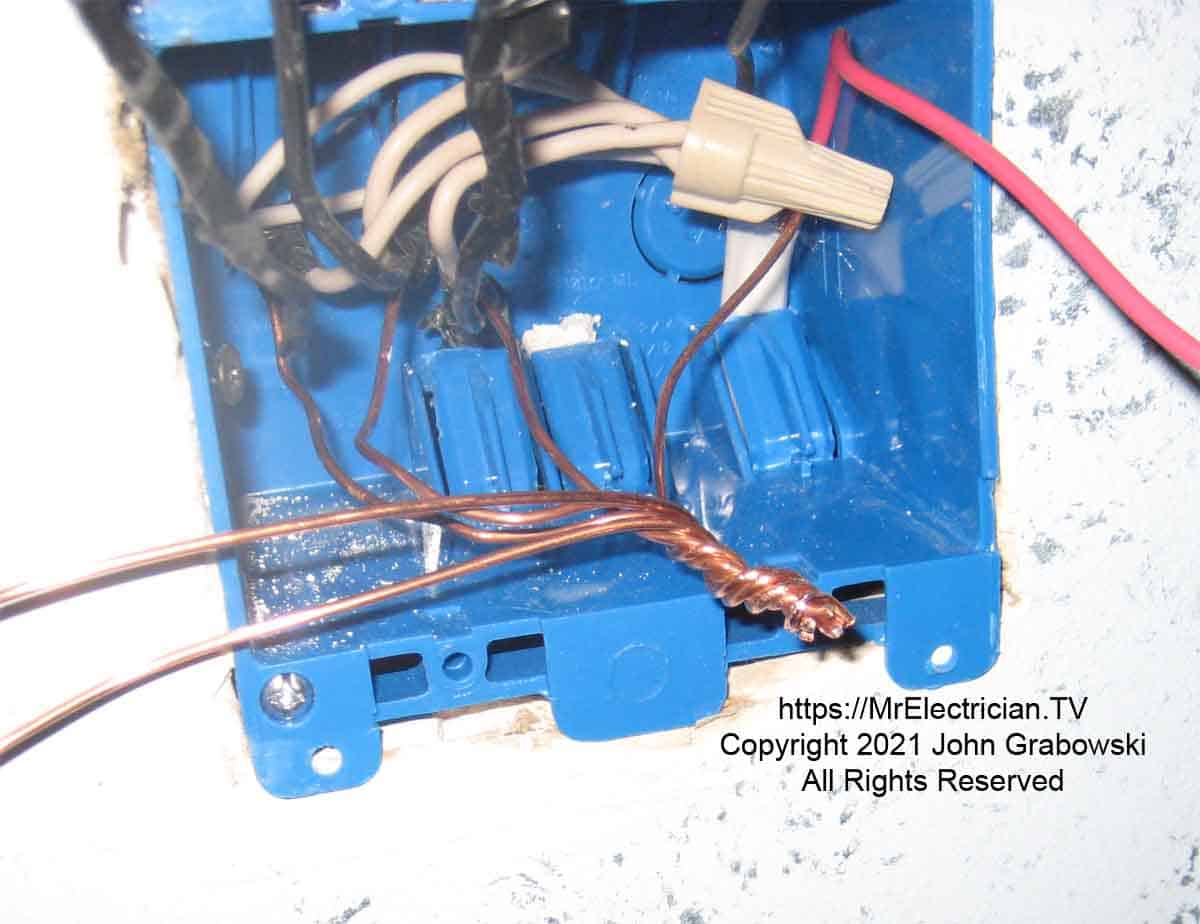 Twisted grounding wires and pigtails in a two-gang plastic switch box awaiting a big wire connector