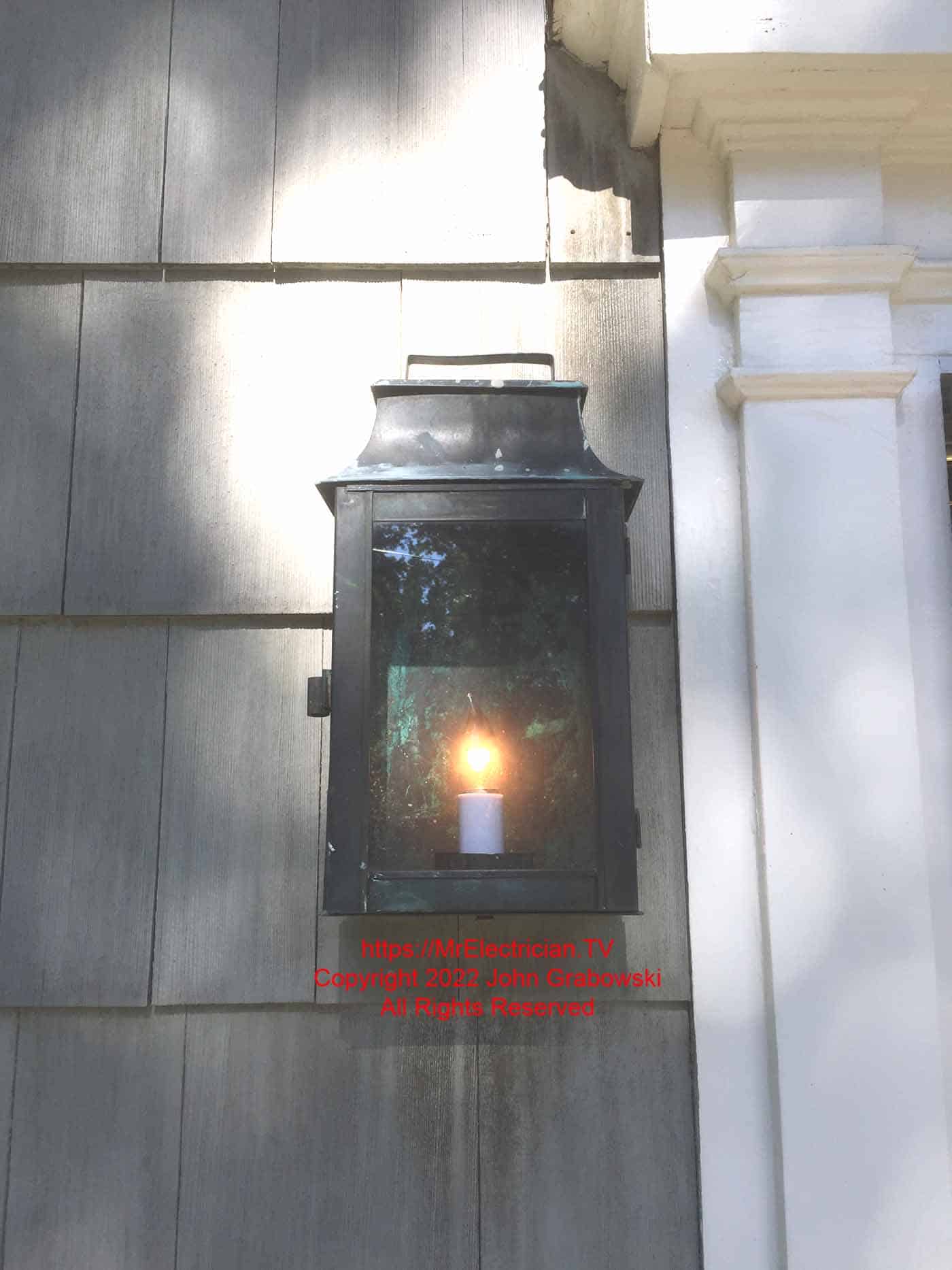 Antique copper electric lantern mounted outdoors next to the front door