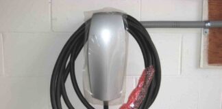 A Tesla electric vehicle charger mounted on a garage wall with factory protective wrapping still on.