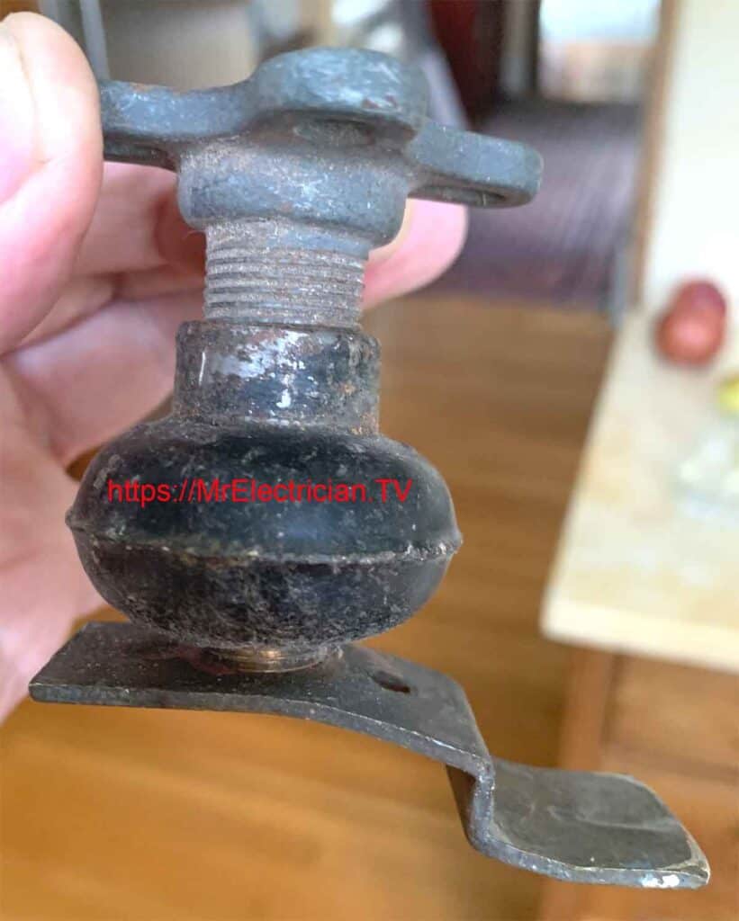 A photo of some electrical lighting fittings from a house built in 1910. The parts include a crowfoot fixture hanger, an electrical insulator, and a bracket to support a wall sconce. A photo of some electrical lighting fittings from a house built in 1910. The parts include a crowfoot fixture hanger, an electrical insulator, and a bracket to support a wall sconce.