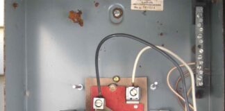 The interior of an active outdoor electrical panel with a white wire being used as one of the LINE conductors feeding the panel. The equipment grounding conductor is being used as a neutral which can cause phantom voltage.