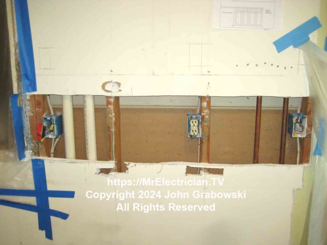 The image depicts three electrical outlet boxes exposed, along with the easy-to-find wood wall studs, two plastic pipes and two copper pipes during the demolition phase of a kitchen remodel.