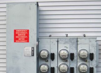 A main electric disconnect switch connected to nine electric meters attached to the side of a residential building. The disconnect switch is labeled Emergency Disconnect, Service Disconnect, Meter Disconnect.