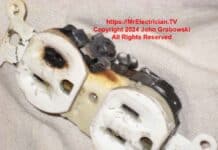 An electrical outlet with a burned slot on the face and a burned screw on the side.