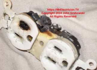 A burned electrical outlet with a toasted slot on the face and a burned screw on the side.
