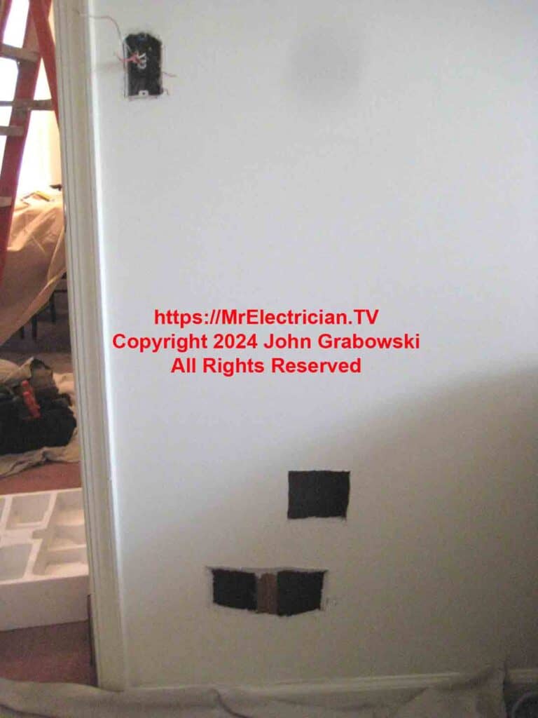 An electrical wall switch with holes cut in the wall below to add outlets from the existing switch.