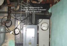 An older electric meter and fuse box located inside a basement adjacent to the foundation wall. The armored grounding electrode conductor is coming out of the bottom of the meter socket.