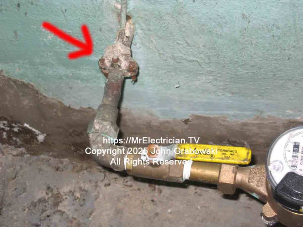 A corroded water pipe ground clamp with an armored grounding electrode conductor attached.