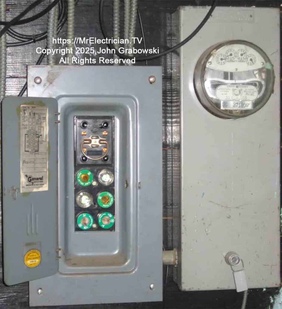 An old electric service fuse box in good working condition attached to the basement installed electric meter. The armored grounding electrode conductor is coming out of the bottom of the meter socket. The power company employees have a special key to unlock and remove the meter socket cover.