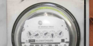 A close shot of an older General Electric watt-hour electric meter that measures electricity consumption using kilowatt-hours