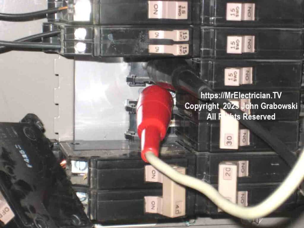 Red and a black spring loaded metal clip-ons temporarily attached to the main electrical bus bars in a Cutler-Hammer type CH residential electrical load center