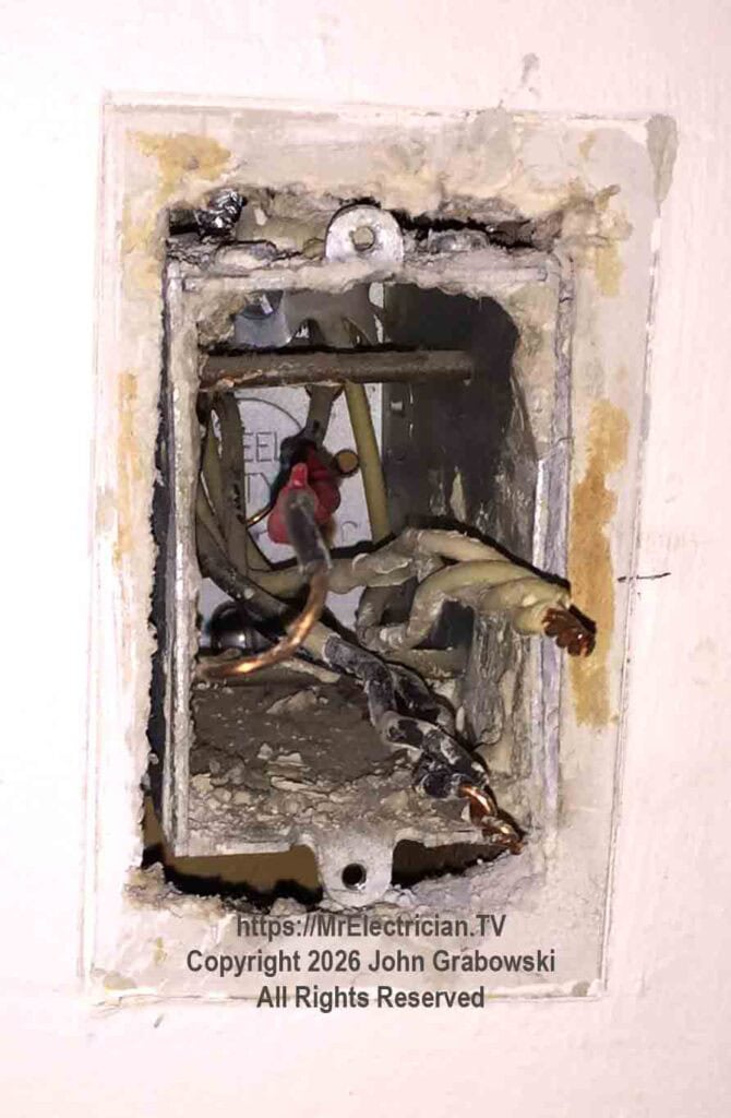 An older in-wall, one-gang metal switch box with three cables entering through the top inside. Three white wires are joined together. This switch box has a neutral