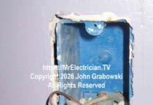 An ivory colored electrical wall switch hanging from a blue plastic switch box by a white wire, a black wire, and a bare copper wire. There is no neutral available here.